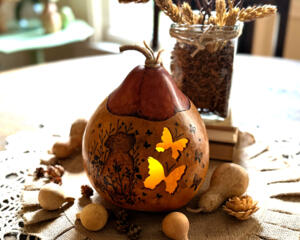 A gourd luminary with dog in garden artwork. Battery-operated candle light shines through two butterflies carved out of the gourd shell.